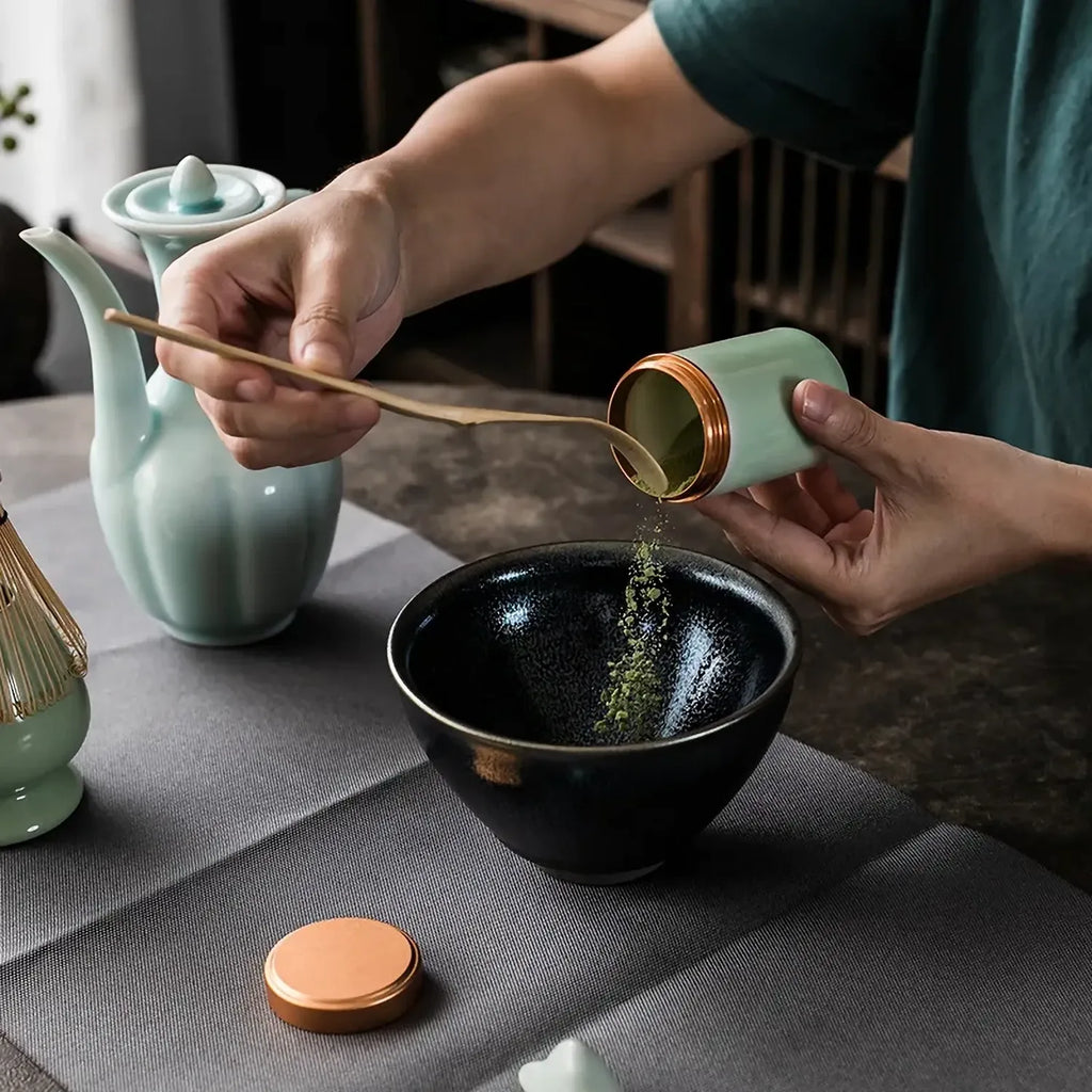 Geste de preparation du matcha avec versement dans le bol noir du set Chado