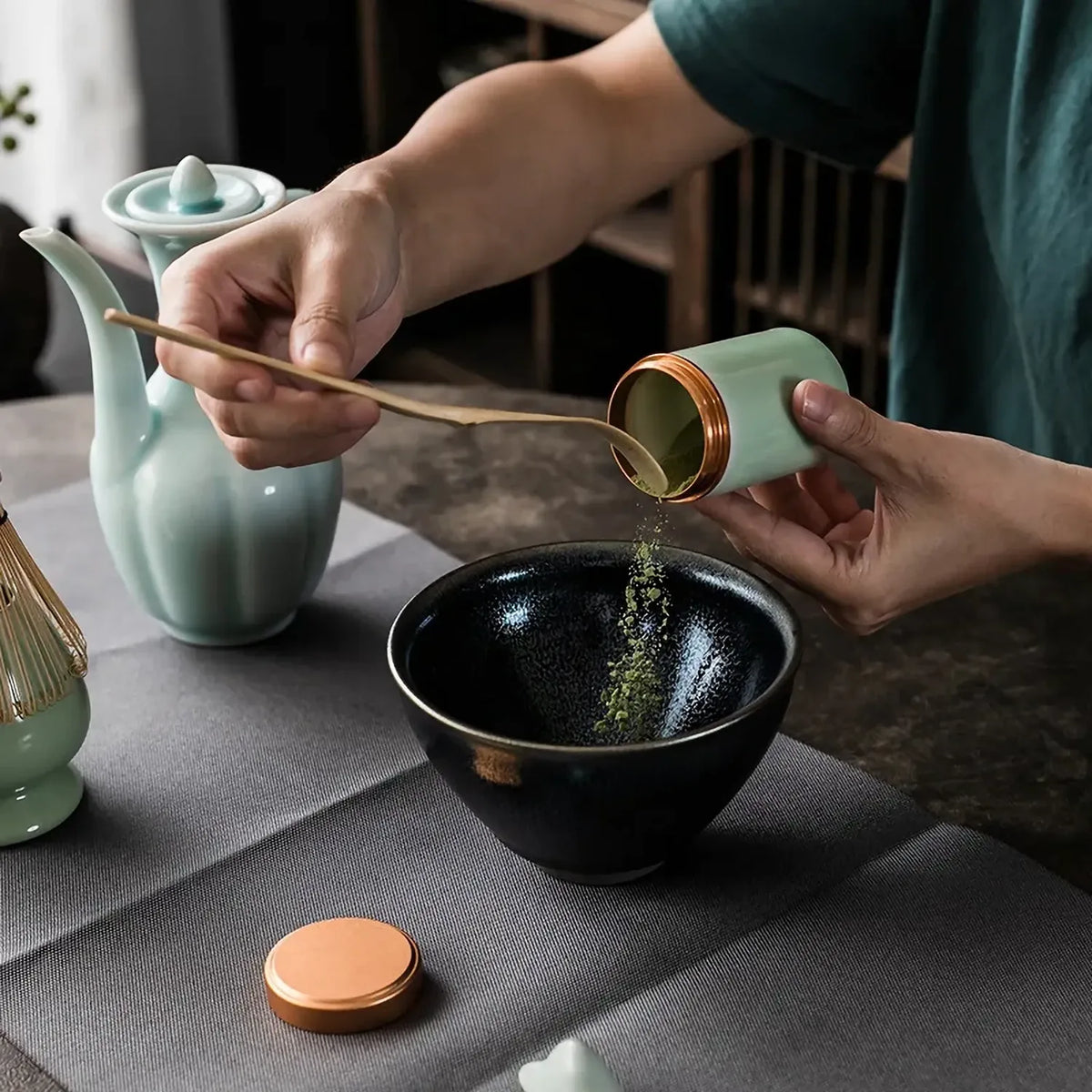 Geste de preparation du matcha avec versement dans le bol noir du set Chado