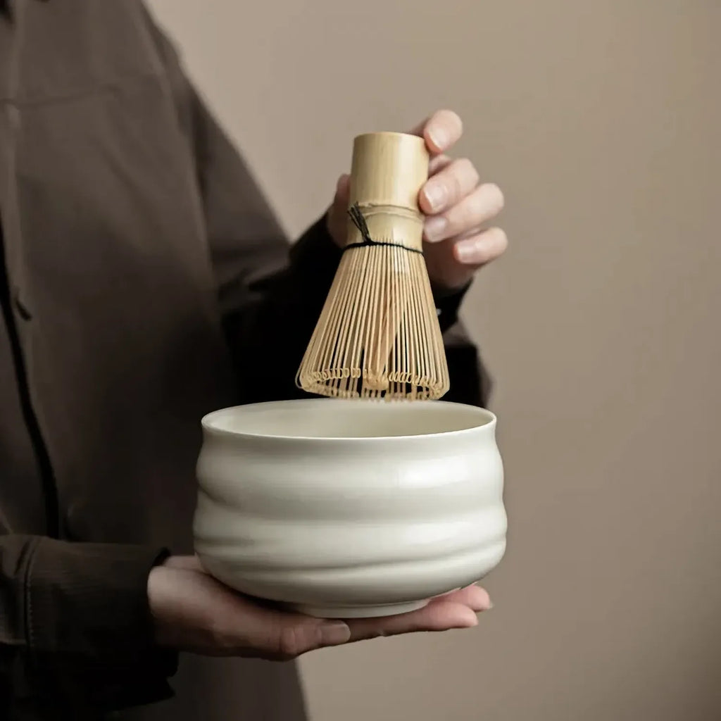 Main tenant le bol chawan et le chasen du set matcha Tsubaki